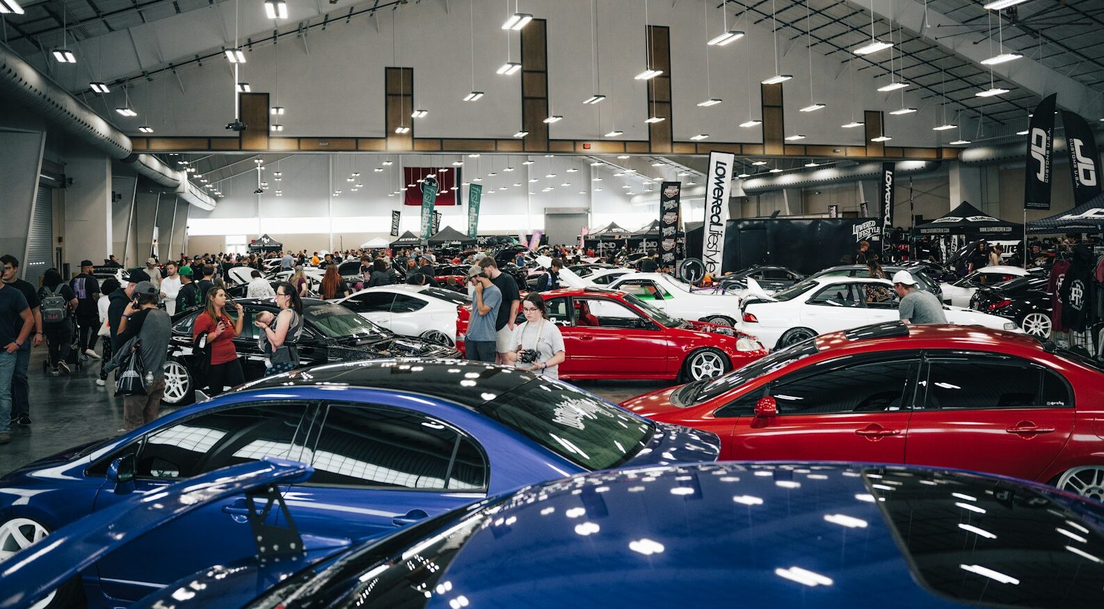 a group of people looking at cars in a showroom