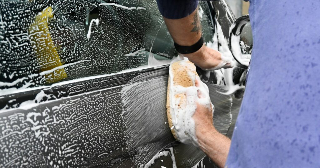 a man washing a car with a sponge